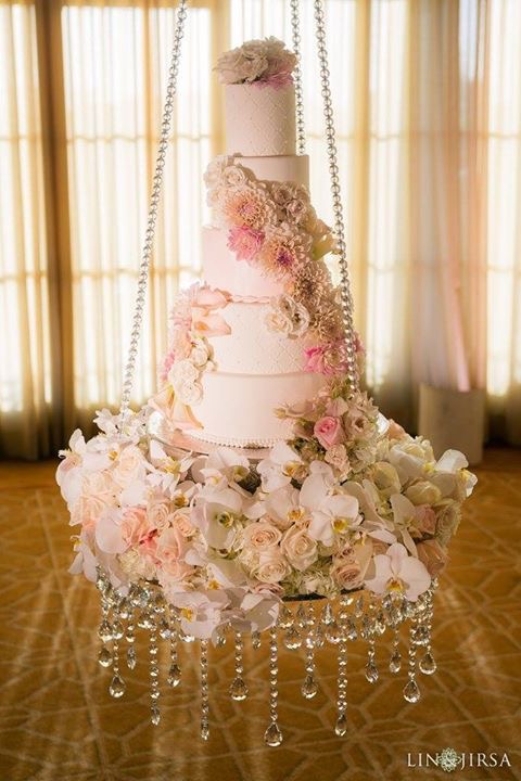 Tiered wedding cake decorated with cascading pink flowers